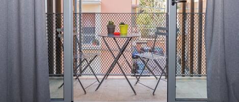 Een balkon met een tafel, stoelen en plantenpotten.