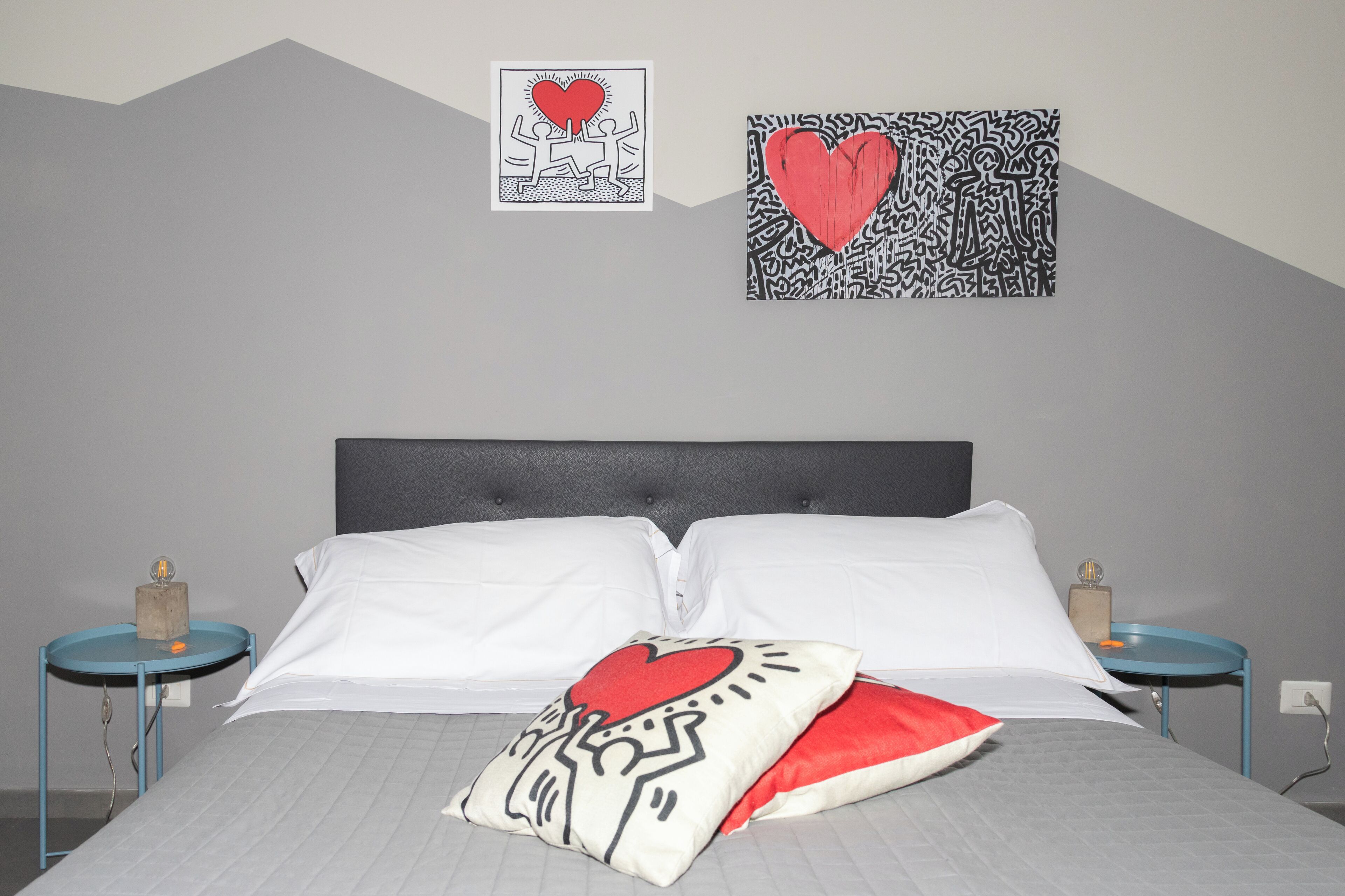 Een slaapkamer met een bed, twee nachtkastjes en twee decoratieve wandobjecten.