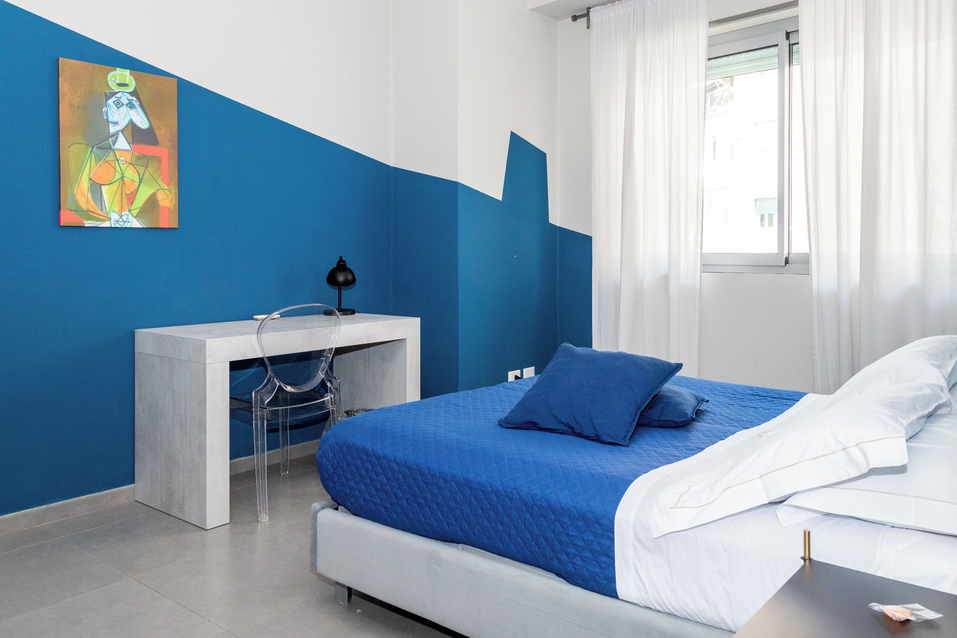 A bedroom with a bed, a desk, and a chair.