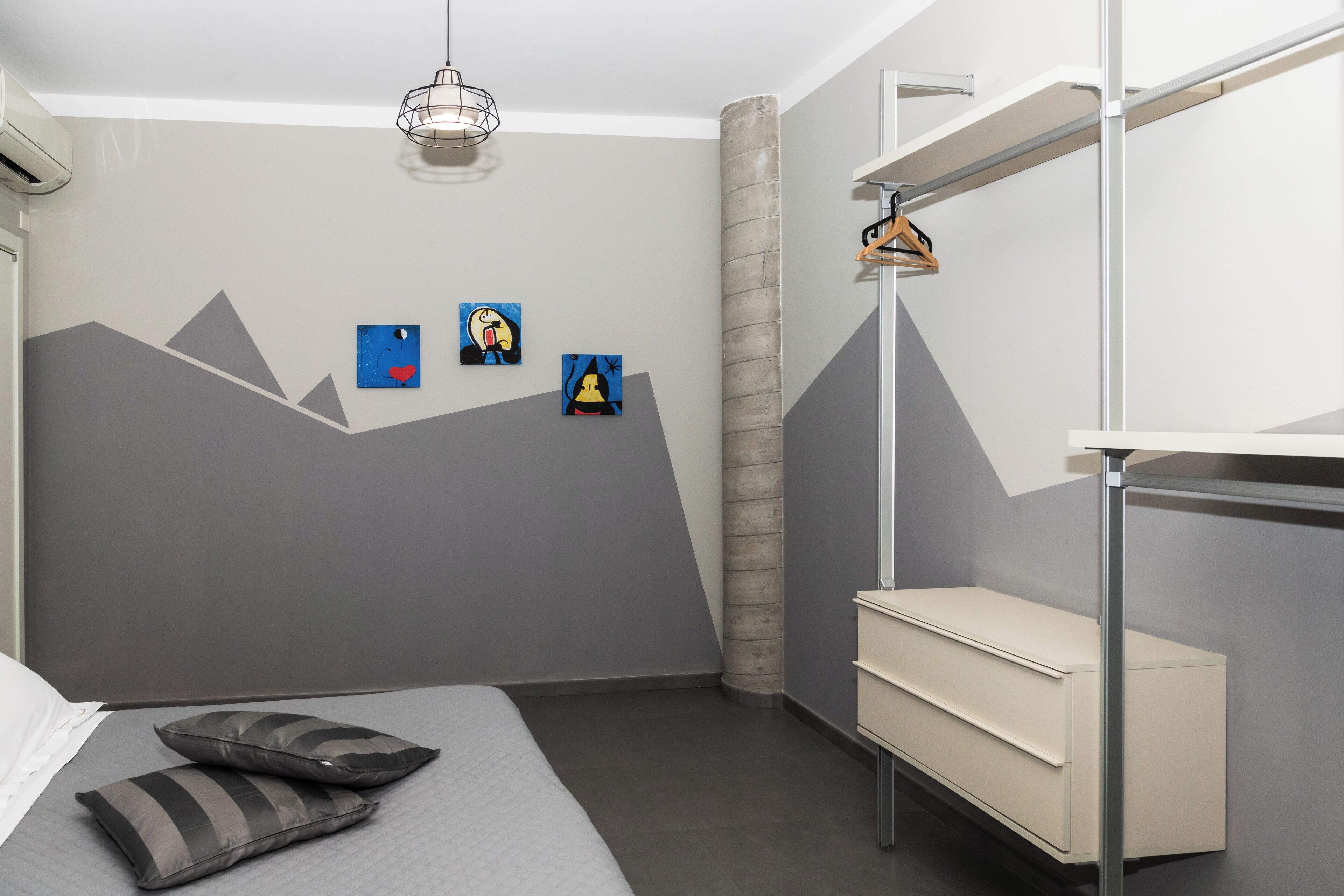A modern bedroom with a bunk bed, a bedside table, and a wall-mounted shelf.