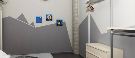 A modern bedroom with a bunk bed, a bedside table, and a wall-mounted shelf.