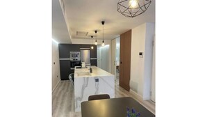 Une cuisine moderne dotée d’un plan de travail en marbre, d’un revêtement de sol en bois et de luminaires suspendus.