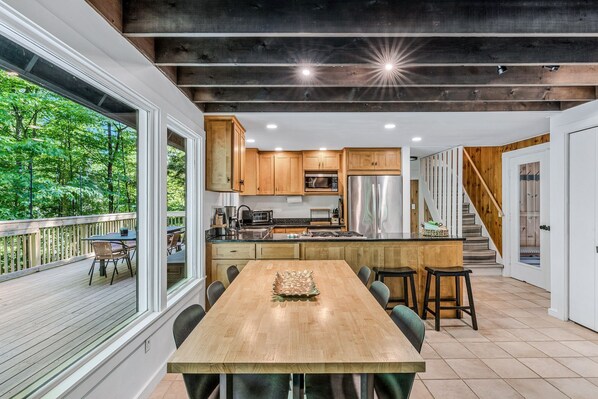 Une cuisine moderne avec des meubles en bois, un îlot central et un coin repas comprenant une grande table et des chaises.