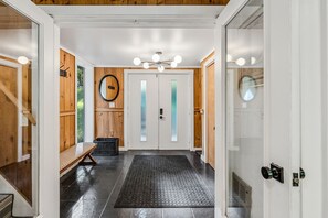 A hallway with a bench, a door with frosted glass panels, and a ceiling light fixture.
