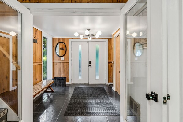 A hallway with a bench, a door with frosted glass panels, and a ceiling light fixture.