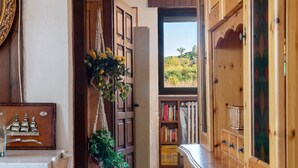 Ein Holzinnenraum mit Bücherregal, Pflanze und Blick durch eine Tür.
