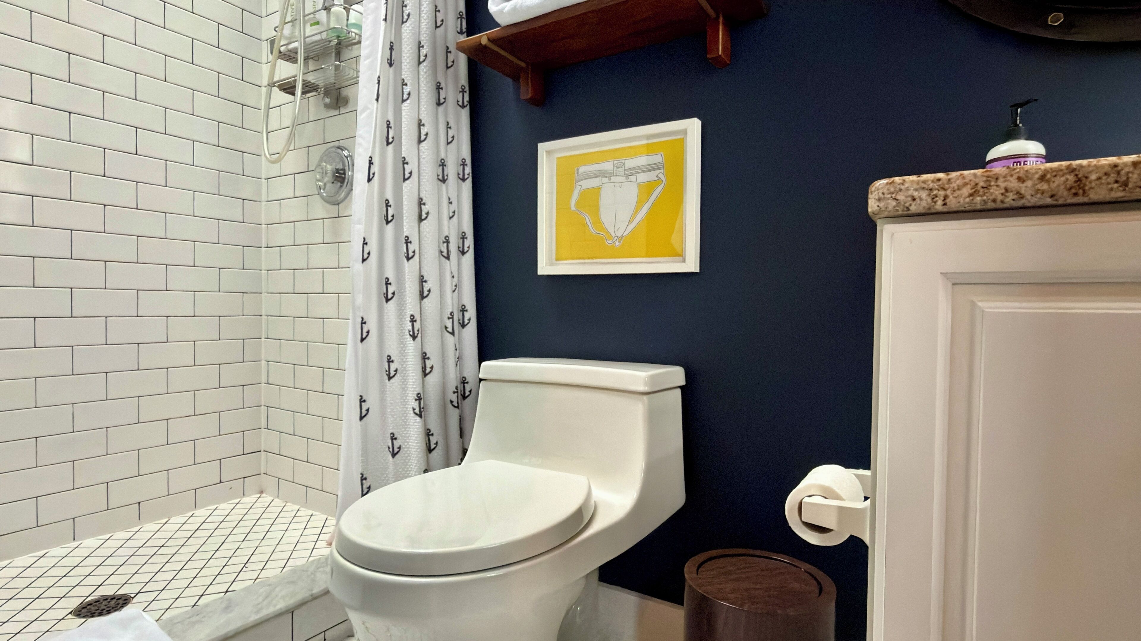 A bathroom with a white toilet, a shower with a white tiled wall, and a blue accent wall.