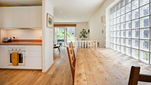 Une cuisine moderne avec des meubles blancs, un plan de travail en bois et une grande fenêtre donnant sur un paysage verdoyant.