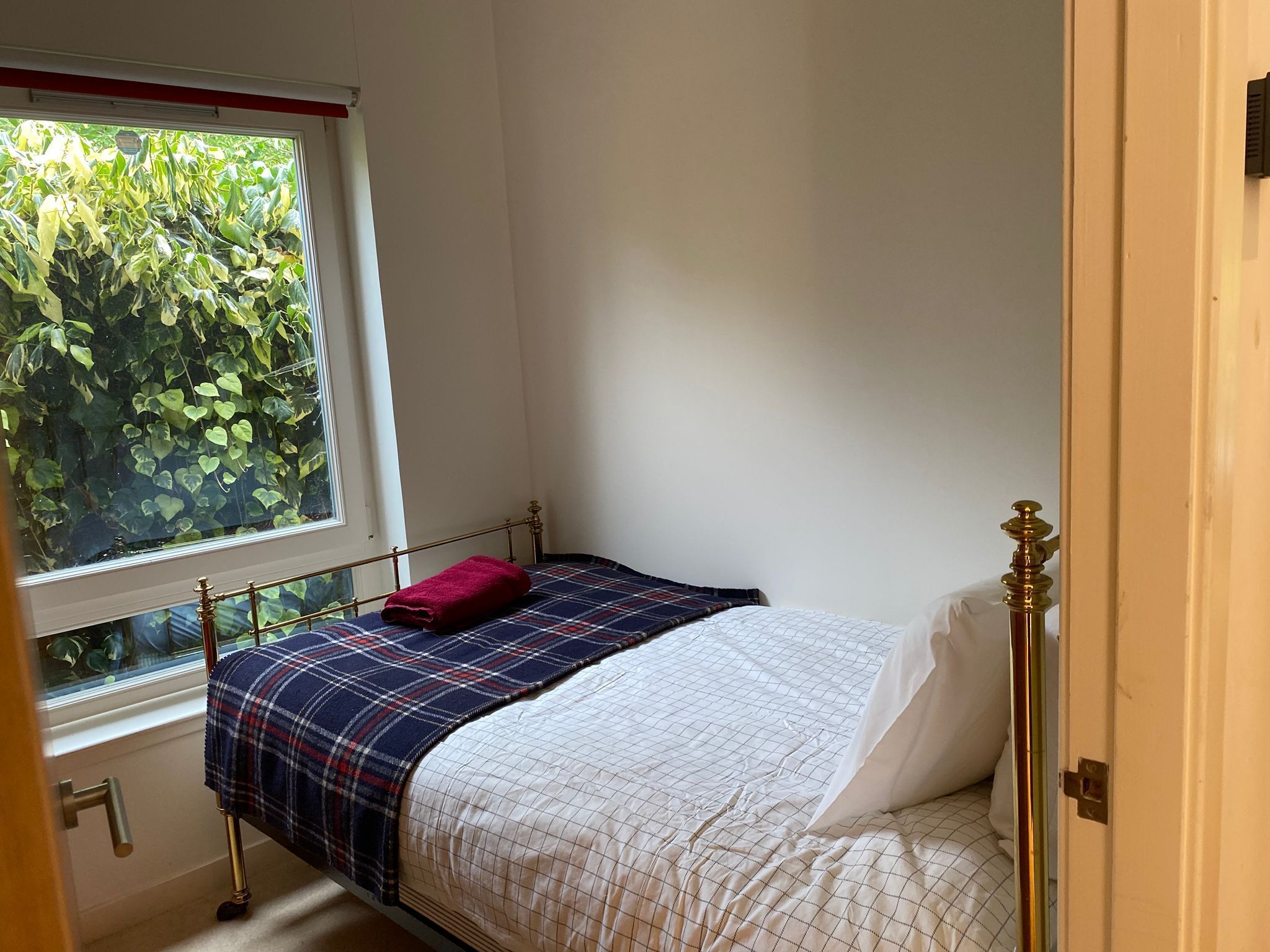 A small, single-bed room with a window overlooking greenery.