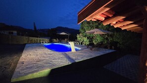 A swimming pool with a waterfall feature, surrounded by a stone patio and outdoor furniture. - Chácara Martinetti (Águas da Prata)