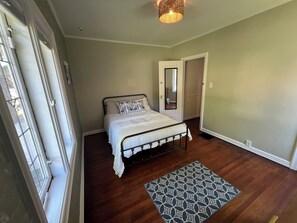 A bedroom with a bed, a patterned rug, a door, and a window.