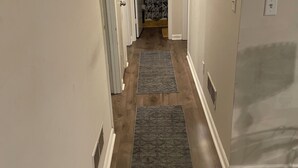 Un couloir avec un plancher en bois, un rideau à motifs floraux et une pancarte au-dessus d’une porte.