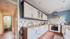 A modern kitchen with white cabinets, a microwave, and an oven. There is a tiled backsplash and a wooden countertop. - Spacious 4-bed, 4-bath home with garden and parking (Berkshire)