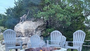 Un foyer entouré de fauteuils Adirondack, avec en arrière-plan des rochers et des arbres.