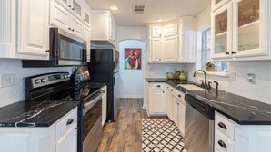 Une cuisine moderne avec des meubles blancs, un plan de travail noir et un sol à motifs.