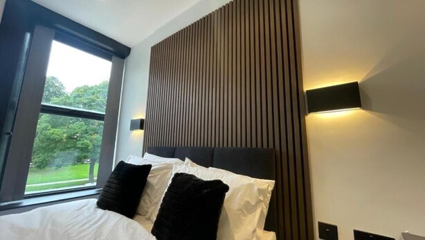 Ein Schlafzimmer mit einem Bett, einem Fenster und einer Wandleuchte.