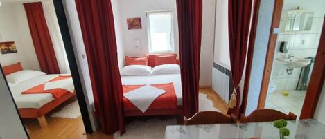 A hotel room with two beds, a bathroom, and a dining area.