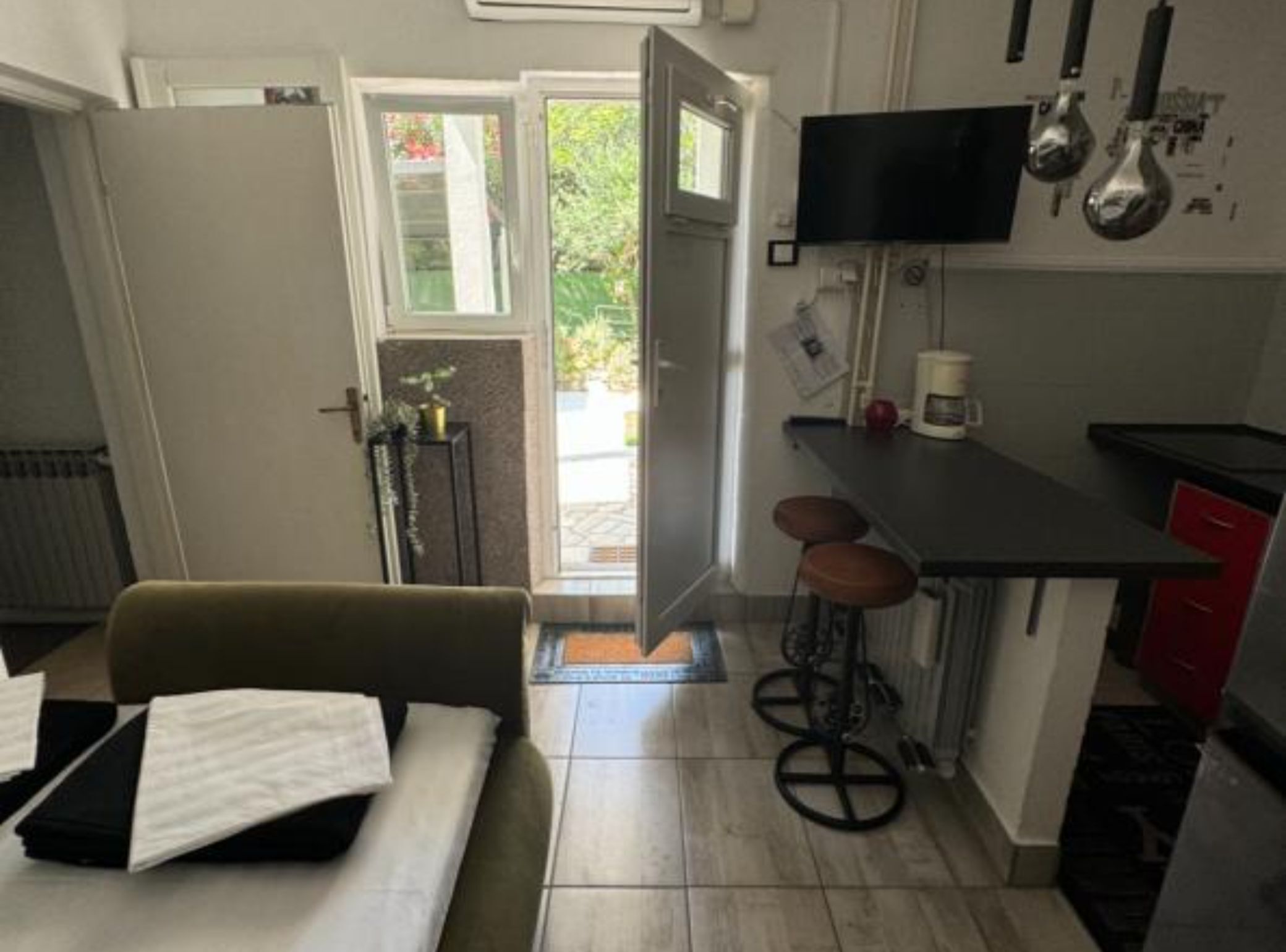 Una cocina compacta con comedor, un televisor sobre la encimera y un taburete pequeño.