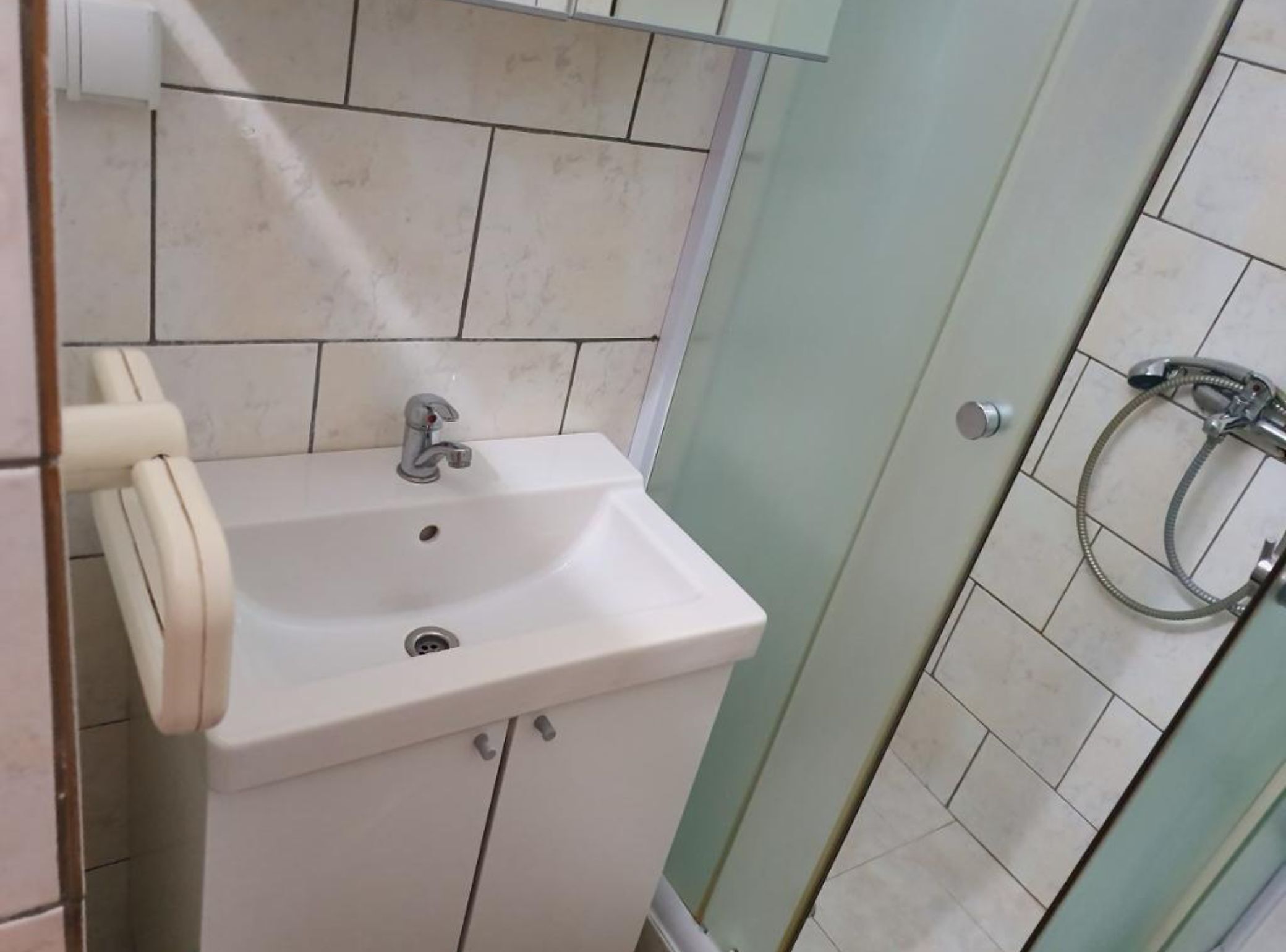 A bathroom with a white sink, a mirror, and a shower area.