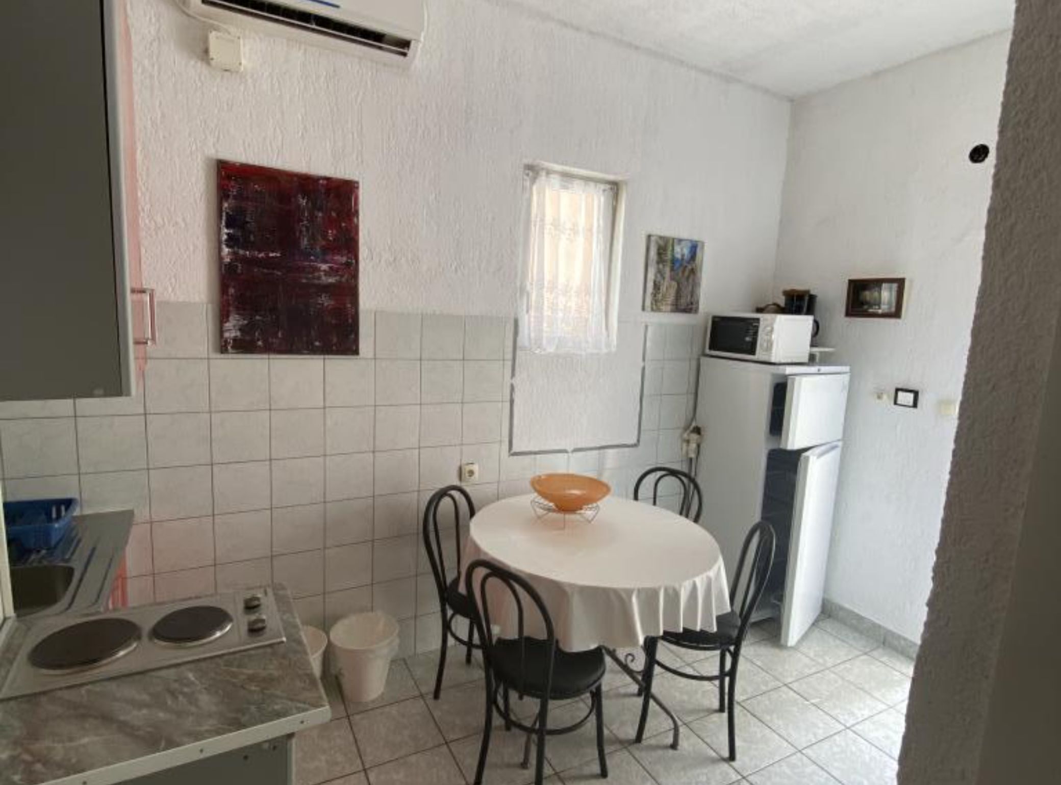 A compact kitchen with a round table, two chairs, a microwave, and a refrigerator.