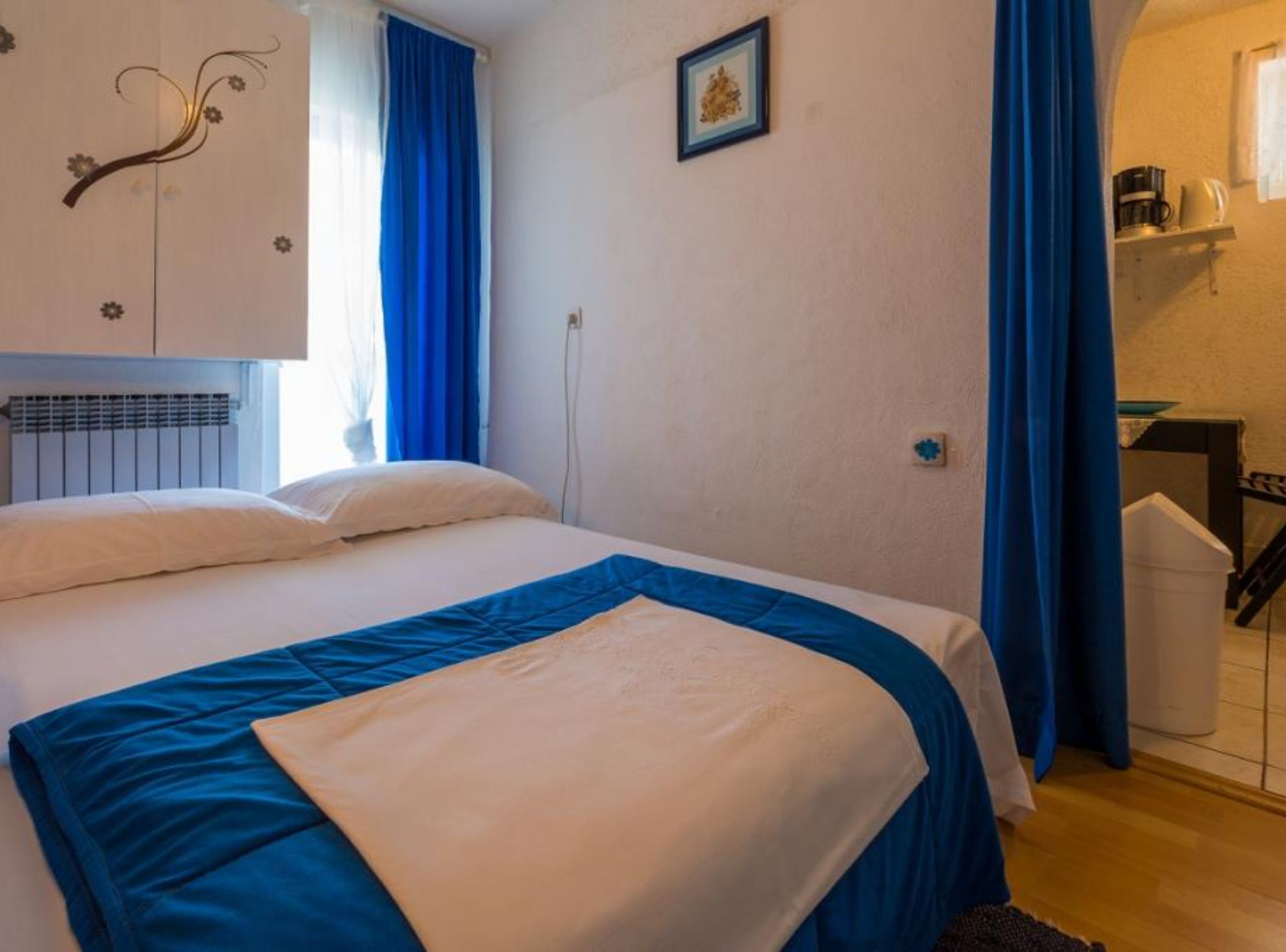A bedroom with a bed, a radiator, a picture on the wall, and a staircase leading to the bathroom.
