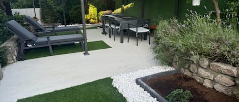 An outdoor patio area with a covered seating area, a pool, and a well-maintained garden.