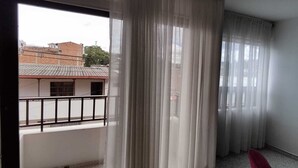 Un balcón con vista a edificios y una silla roja.