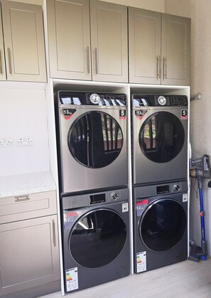 Deux machines à laver à chargement frontal, superposées, dotées d’un panneau de commande, d’une étiquette indiquant une capacité de 13 kg et d’une autre indiquant une capacité de 5 kg.