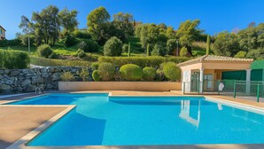 Une piscine avec un mur en pierre et un petit bâtiment doté d’un toit en tuiles.