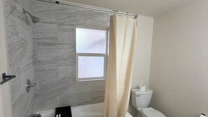 A bathroom with a bathtub, toilet, and shower curtain.