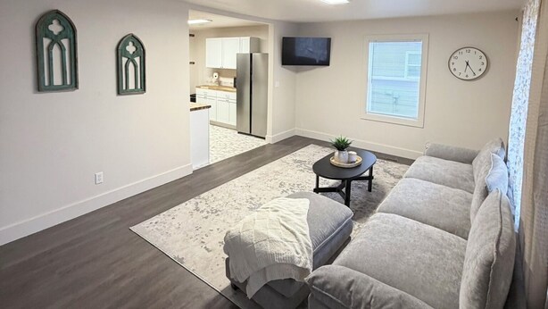 A modern living room with a grey sofa, a coffee table, and a TV mounted on the wall.