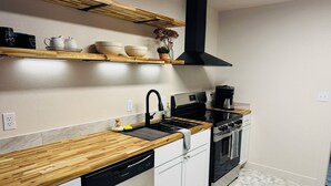 A modern kitchen with a wooden countertop, stainless steel appliances, and a black range hood.