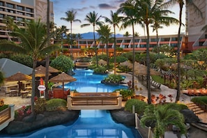 Ein Resort mit Pool, Palmen und einer Brücke.