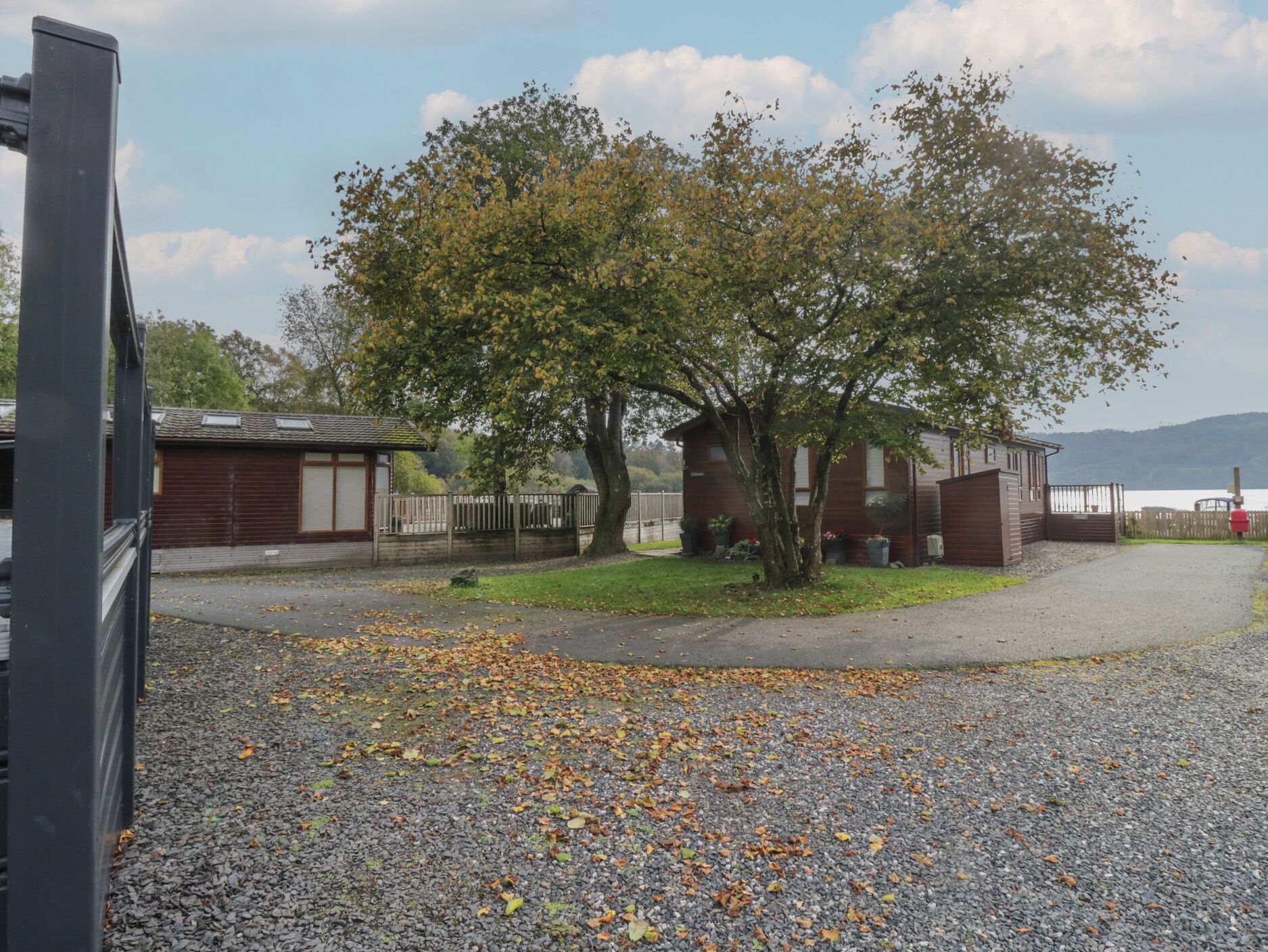 A gravel parking area with a tree and a building.