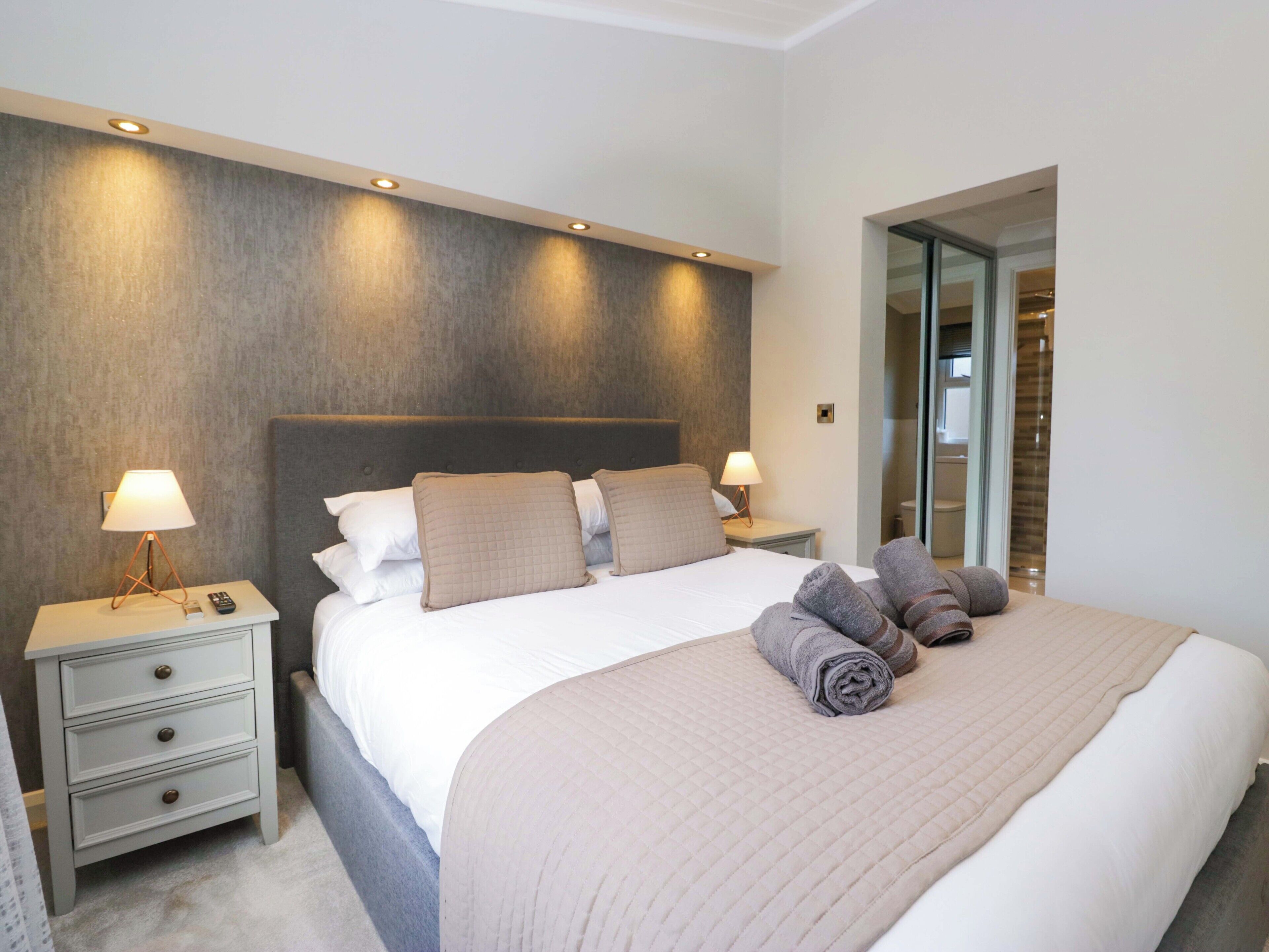 A modern hotel room with a large bed, two bedside tables, and a built-in bench.