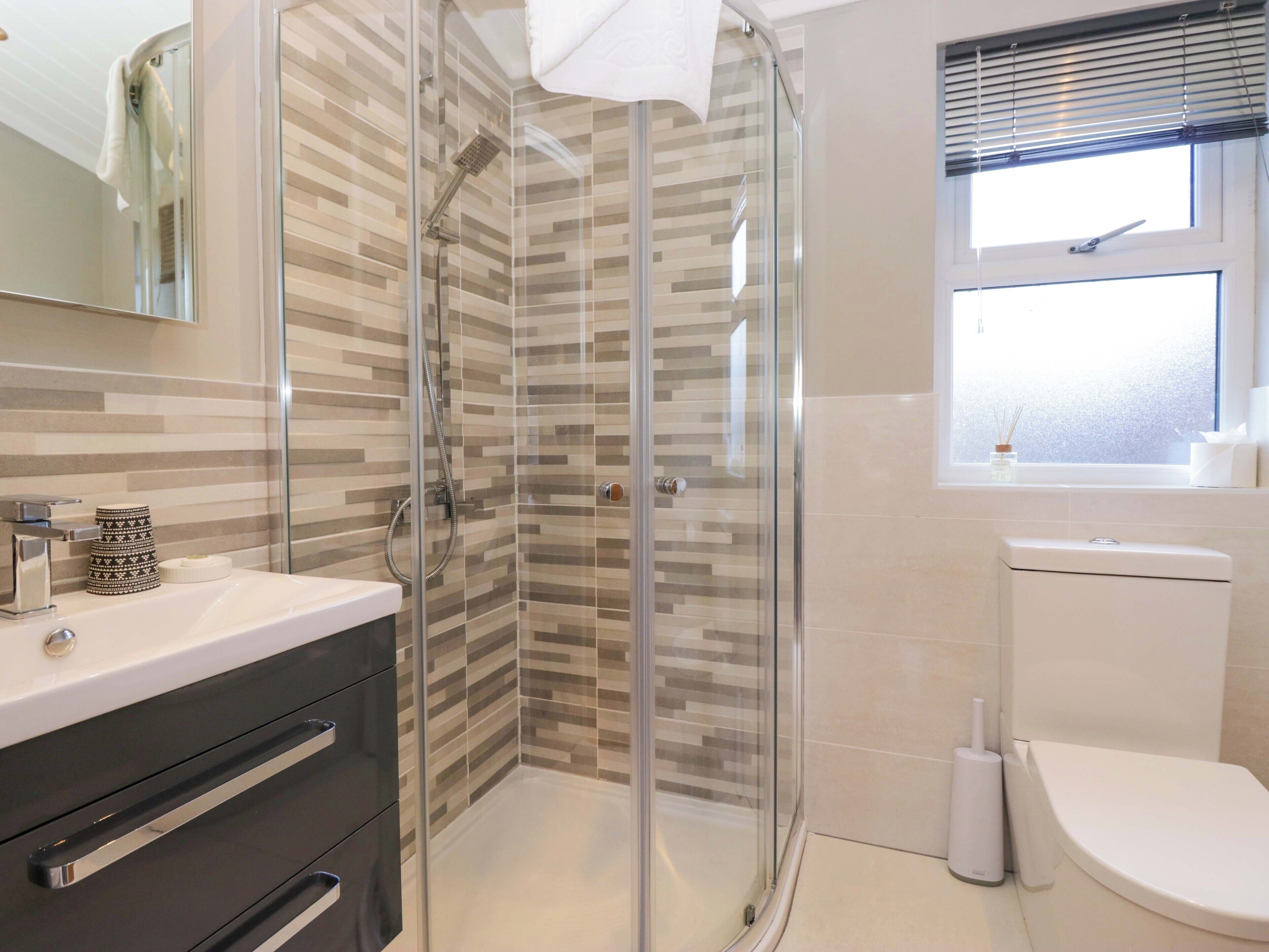 A modern bathroom with a glass shower enclosure, a white sink with a mirror, and a toilet.