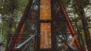 A wooden cabin with a triangular roof, a wooden door, and a metal railing. - Eco village in the forest (Lagodekhi)