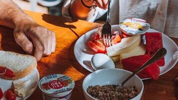 A wooden table with a plate of food, including bread, fruit, and yogurt, and a bowl of what appears to be lentils.