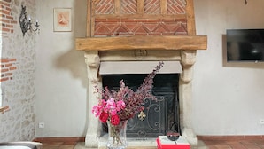 A rustic room with a fireplace, a wooden ceiling, and a cowhide rug. - Maison piscine & tennis partagés (Combreux)