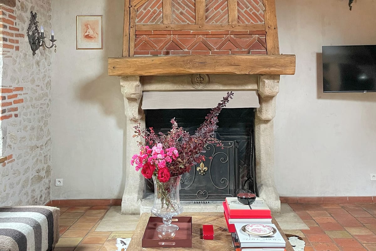 A rustic room with a fireplace, a wooden ceiling, and a cowhide rug.