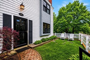 A house with a white exterior, black shutters, a brick pathway, a well-maintained lawn, and a white fence. - *NEW* West End Artsy Gem, Private Patio, Parking (Provincetown)