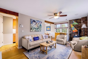 A living room with a sofa, coffee table, and chairs, a fireplace, and a view of the kitchen. - *NEW* West End Artsy Gem, Private Patio, Parking (Provincetown)