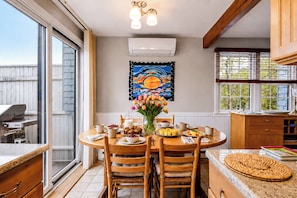 Un coin repas avec une table dressée pour deux personnes, un tableau accroché au mur et une vue sur l’extérieur.