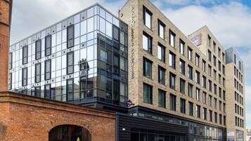 A modern building with a glass facade and a brick section, featuring a storefront with a sign.