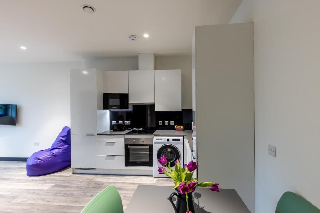 A modern kitchen with built-in appliances, a dining area with a table and chairs, and a purple bean bag chair.