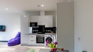 A modern kitchen with built-in appliances, a dining area with a table and chairs, and a purple bean bag chair.