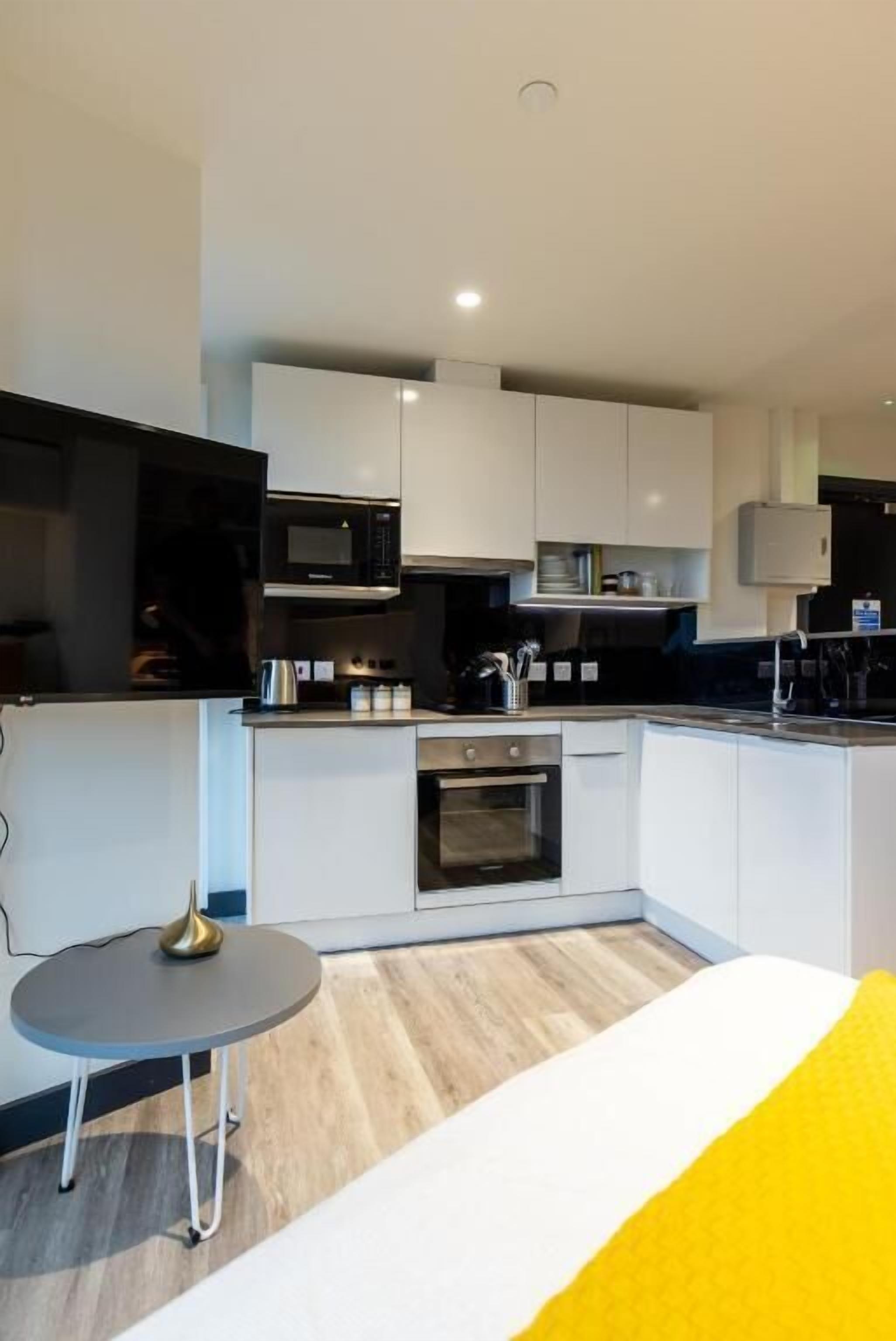 A modern kitchen with white cabinets, a microwave, and a small dining area with a table and chairs.