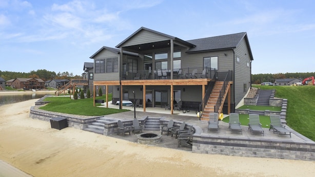 Une maison à deux étages dotée d’un patio couvert, d’un espace salon extérieur et d’un foyer.