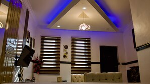 A bedroom with a bed, a TV, a desk, and a window with blinds. - ftrealtyproperties (Accra)