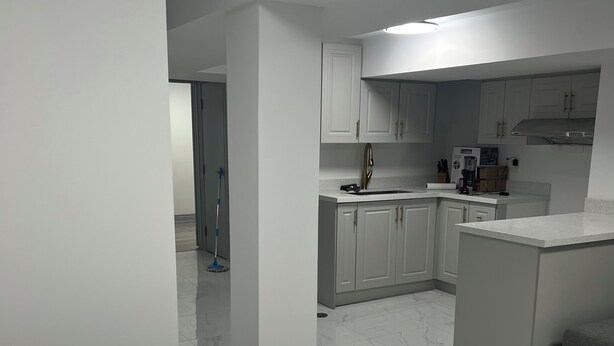 A modern kitchen with white cabinets, a marble countertop, and a built-in oven.